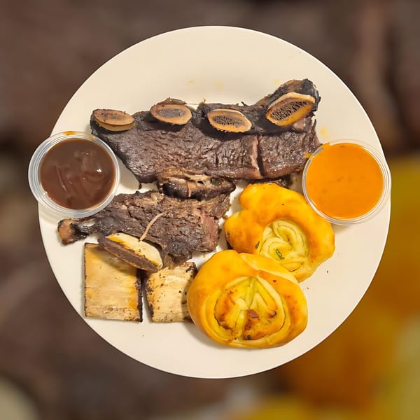 Halal short ribs, flatbread, and two dipping sauces on a white plate at Maza Grill.