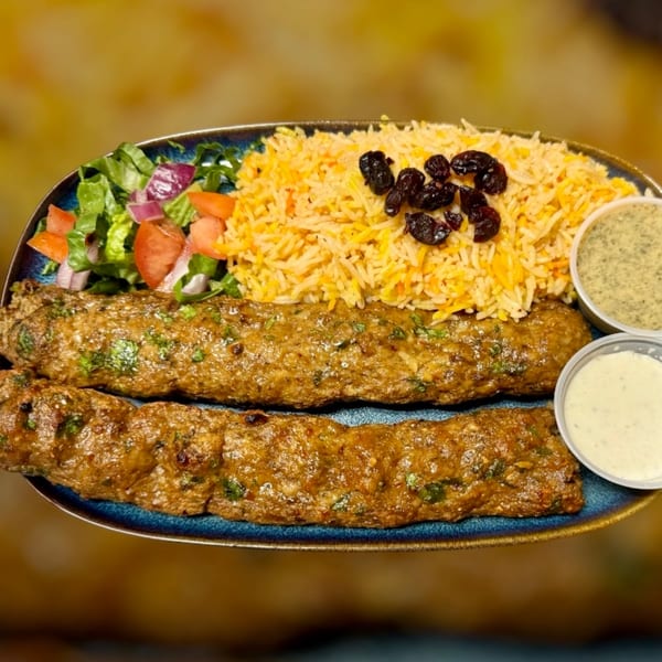 Two Maza Grill halal kebabs with rice, raisins, salad, and two sauces on a blue plate.