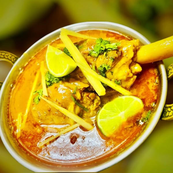 A close-up of Maza Grill's halal nihari, garnished with fresh cilantro, ginger, and lime wedges.